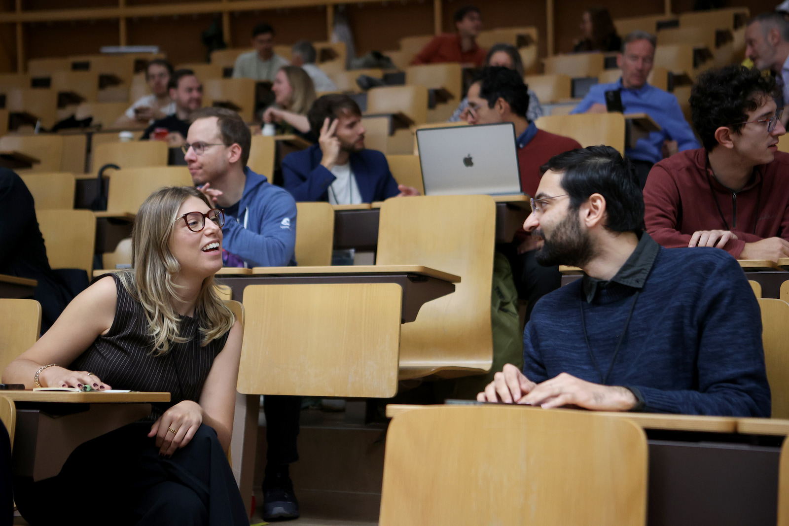 Two attendees talking in the lecture hall between sessions