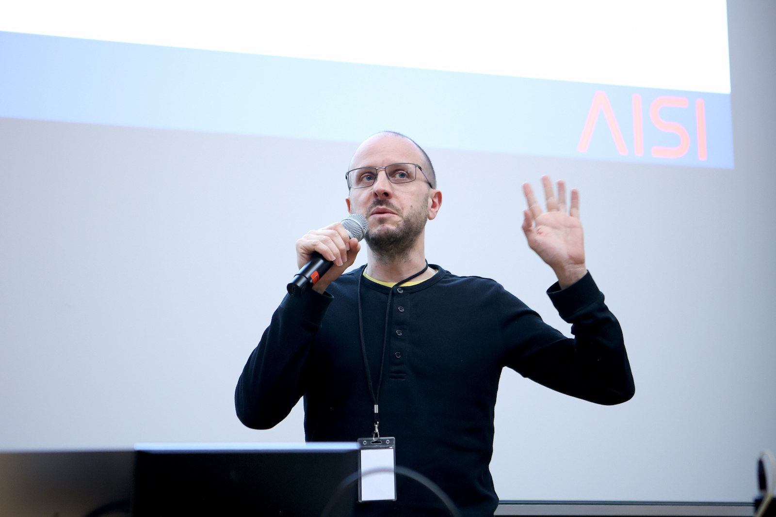 A speaker presenting in front of a UK AI Security Institute slide